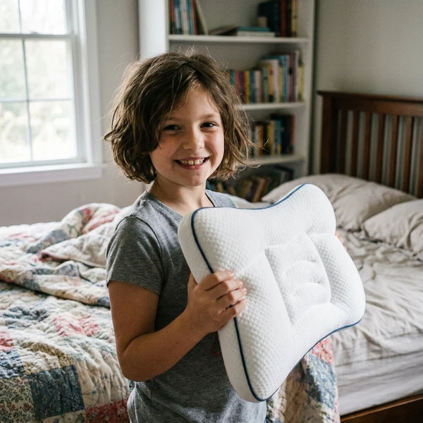 Enfant souriant tenant son oreiller ergonomique